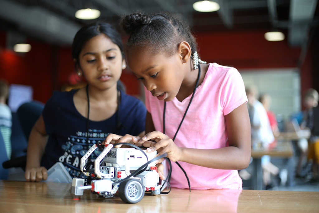 Two female students work on building a robot.
