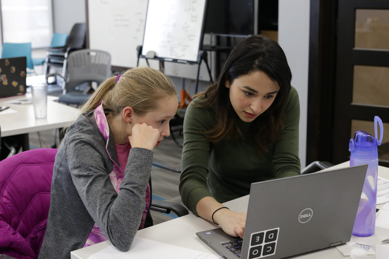 NewBoCo Volunteer Asmaa Elkeurti works with a student on a laptop for NewBoCo's Girls Code Camp
