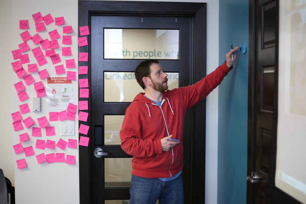 Chief Relationship Officer, David Tominksy posts sticky notes to a wall as he leads a customer discovery workshop