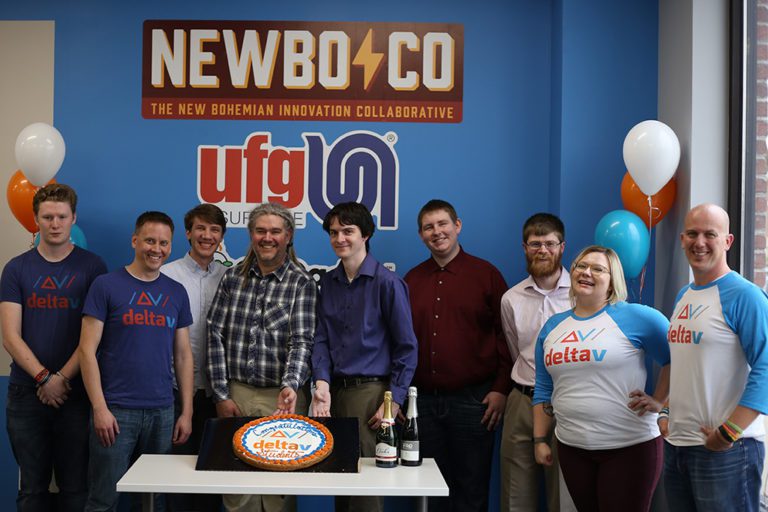 A DeltaV cohort and their instructors celebrate their successful completion of the program by posing with balloons and a cake