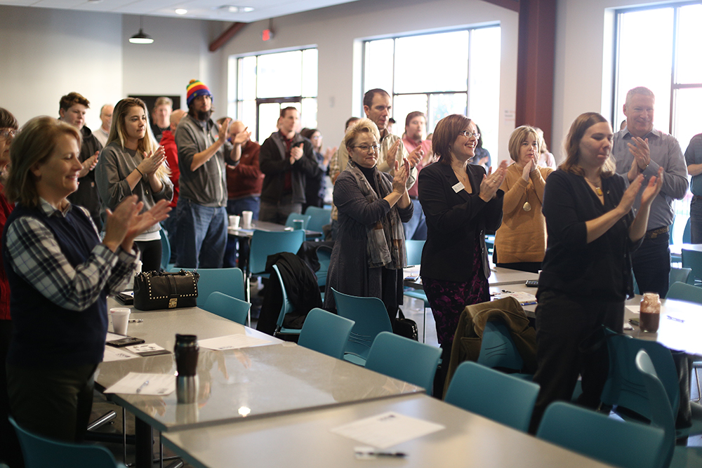 A crowd gives a standing ovation to a presenter at a 1 Million Cups Cedar Rapids event