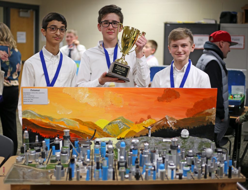 Future City Competition group holding up their champion trophy behind their city model