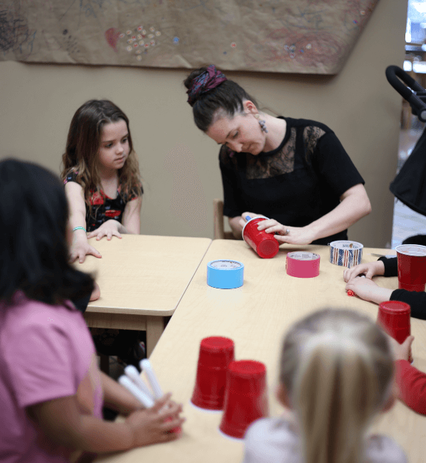 Kaitlin Byers, NewBoCo's Director of Development, assembles a child's project as other children observe