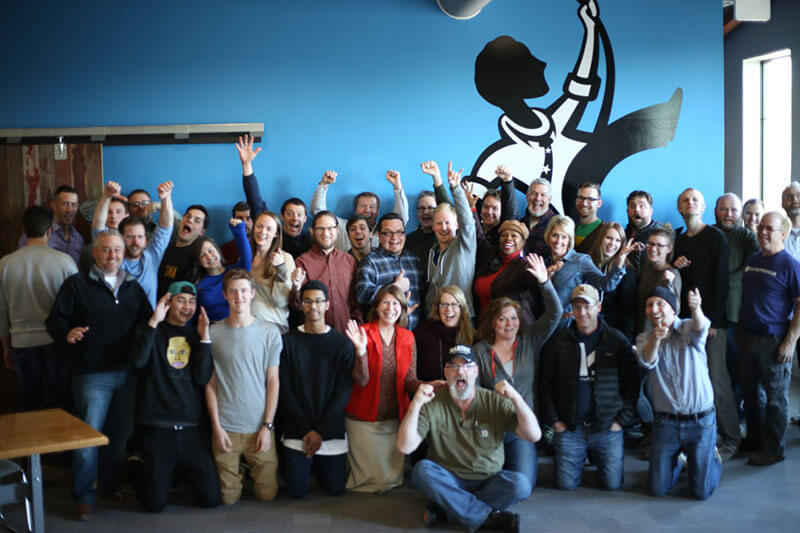 A large group of Vault members gather and pose excitedly in the Vault open office space