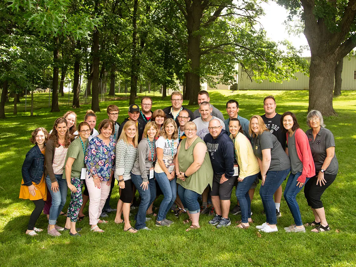 Code.org CS Discoveries summer 2022 teachers gather for a class picture; lush green trees fill the background