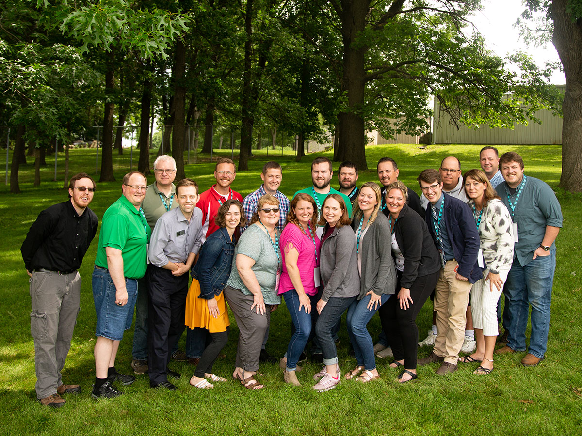 Code.org CS Principles summer 2022 teachers gather for a class picture; lush green trees fill the background