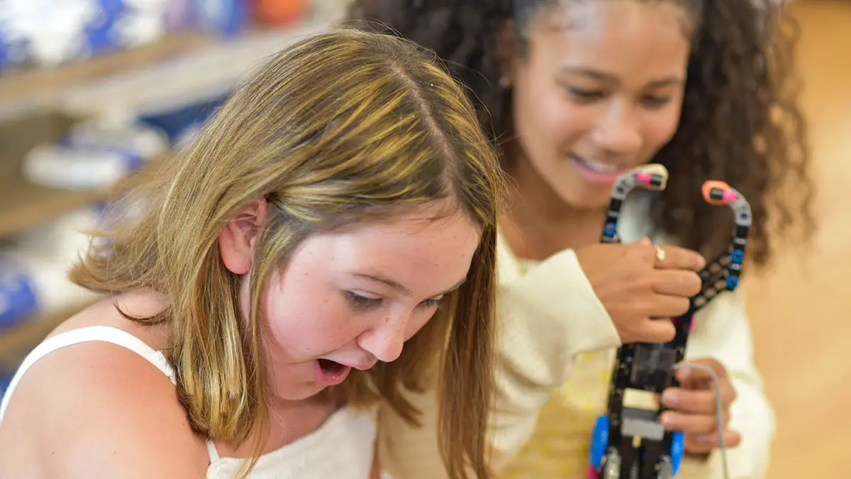 Two CoderDojo students marvel at a "robot arm" they build with consumer building blocks.