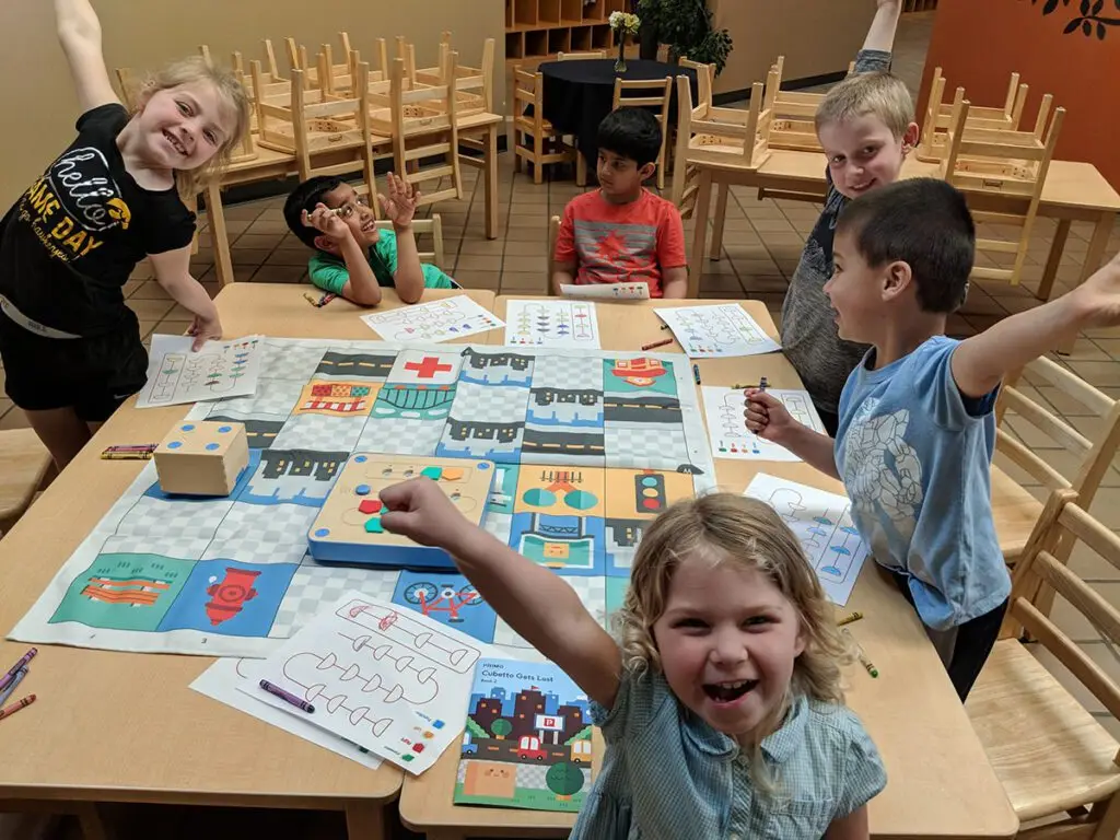 Tiny Techies students cheer around a table lined with project materials