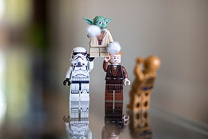Star Wars LEGO figures of a stormtrooper and Anakin Skywalker hoist Yoda over their heads.