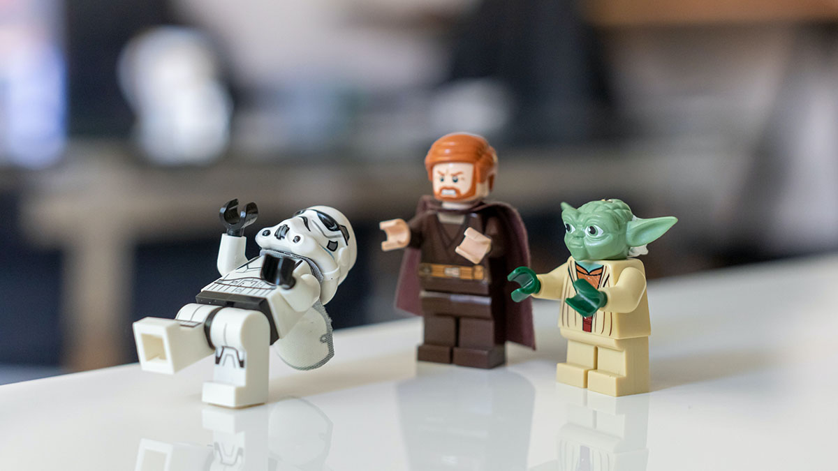 LEGO figures of Yoda and Obi-Wan Kenobi stand behind a LEGO figurine of a stormtrooper