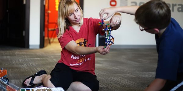 A teacher and a student sit on the floor and assemble a magnetic sculpture together